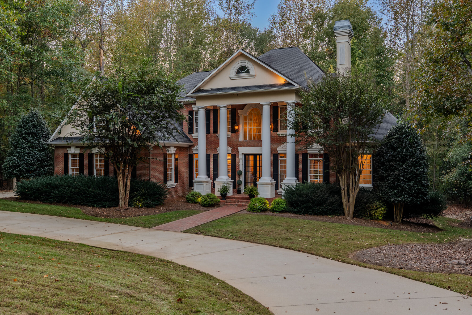 142 Birkdale Drive at dusk, a brick Southern Colonial with a two-story colonnade and circular drive